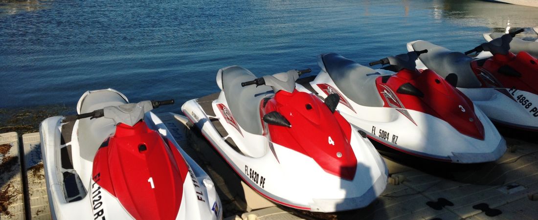 Red and white jet skis docked along the water.